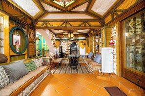 Um interior acolhedor com lareira de pedra, vigas de madeira e piso de azulejos.