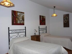 A bedroom with two beds, a nightstand, and wall art.