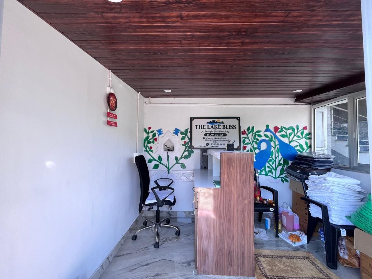 A reception area with a wooden ceiling, a reception desk, a chair, and a wall with a framed sign.