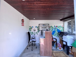 Un'area reception con soffitto in legno, una scrivania, una sedia e un muro con un cartello incorniciato.