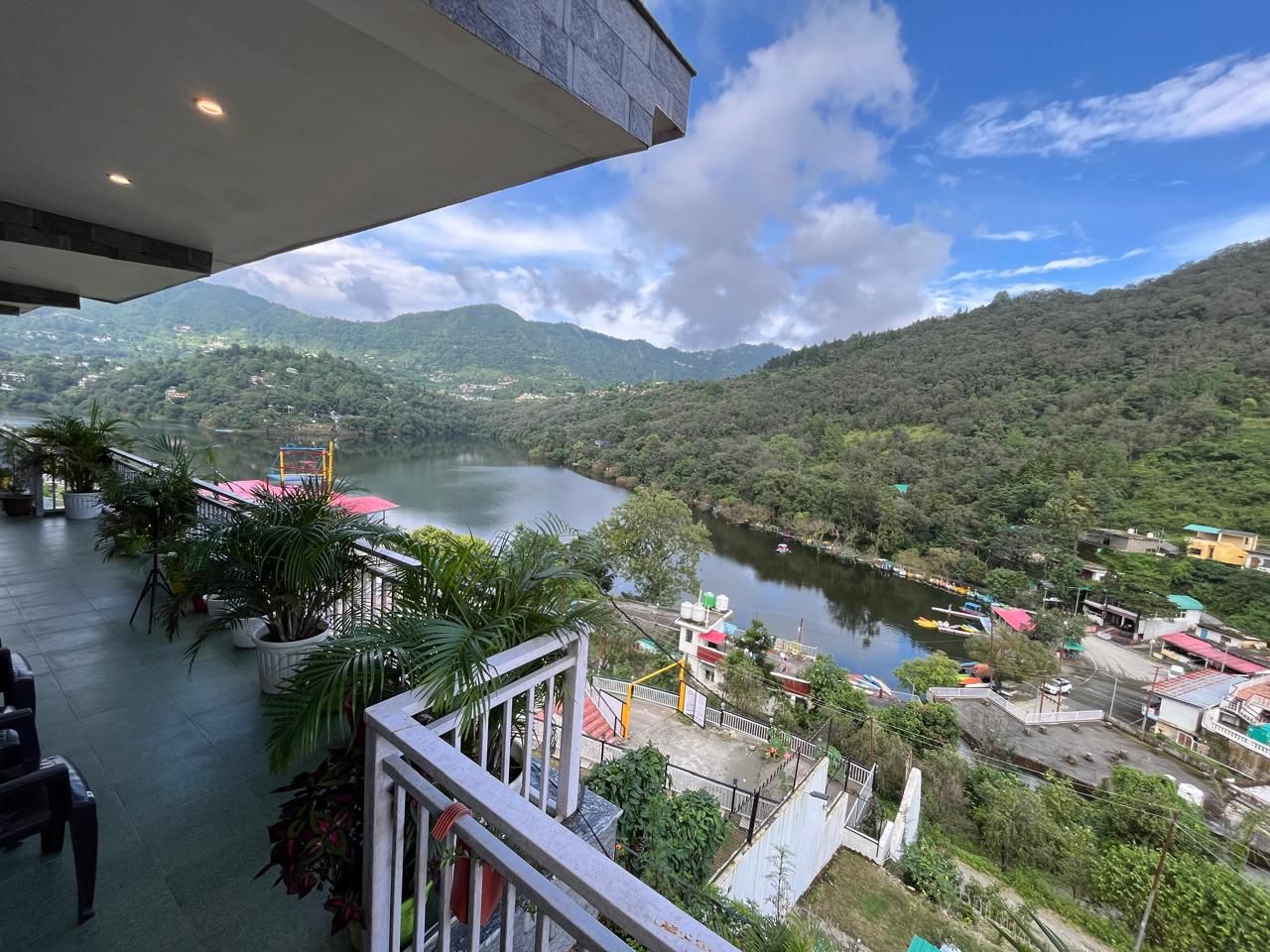Vista al río desde un balcón con plantas en macetas y barandilla.