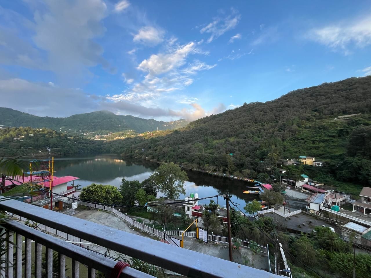 Une vue sur un lac, avec un pont, des bâtiments et une colline boisée.