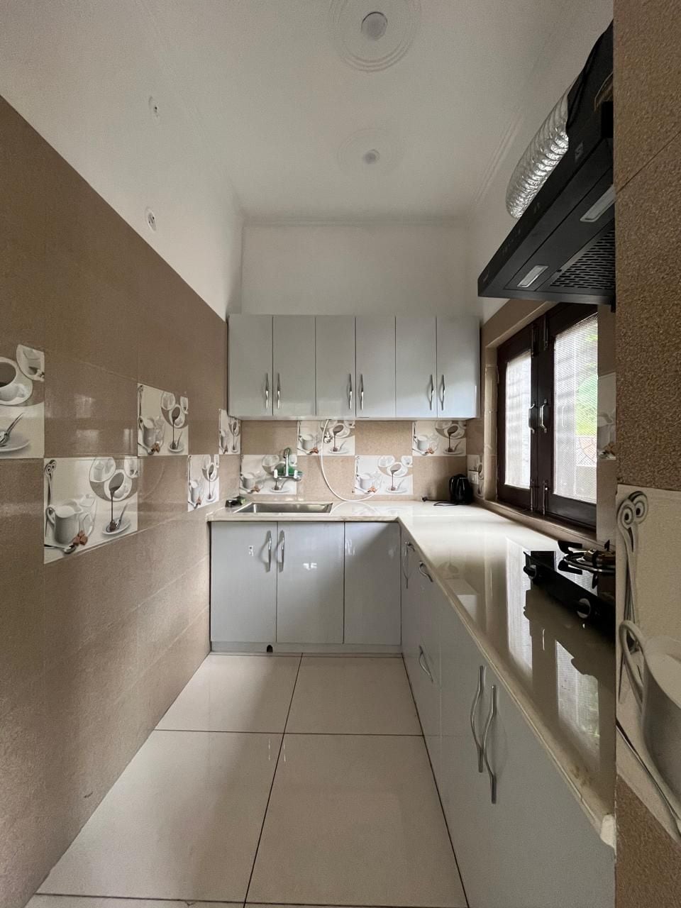 Una cocina con armarios blancos, una encimera y un ventanal.