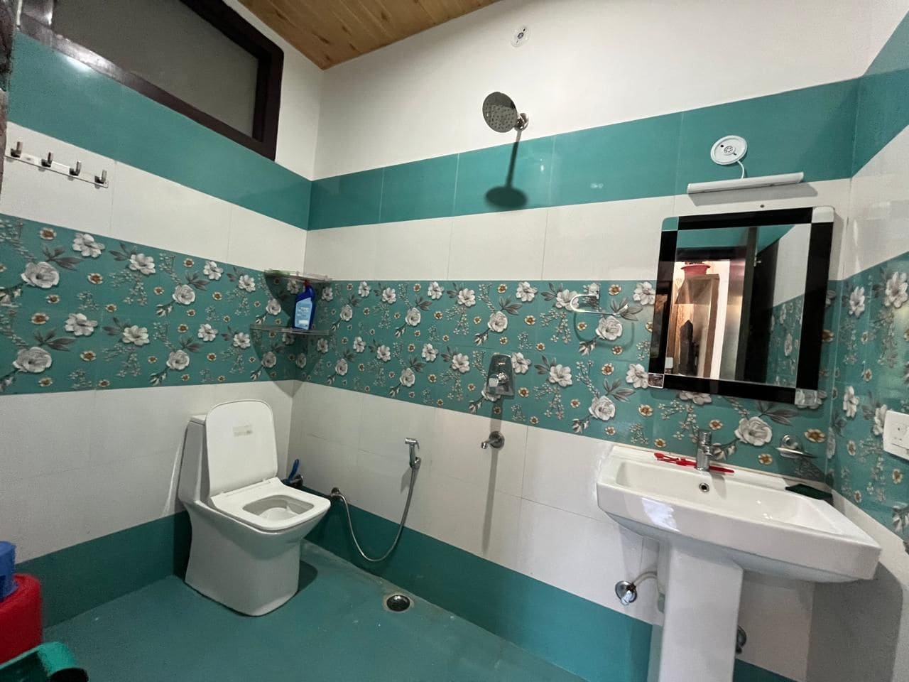 A bathroom with a toilet, shower, and sink.