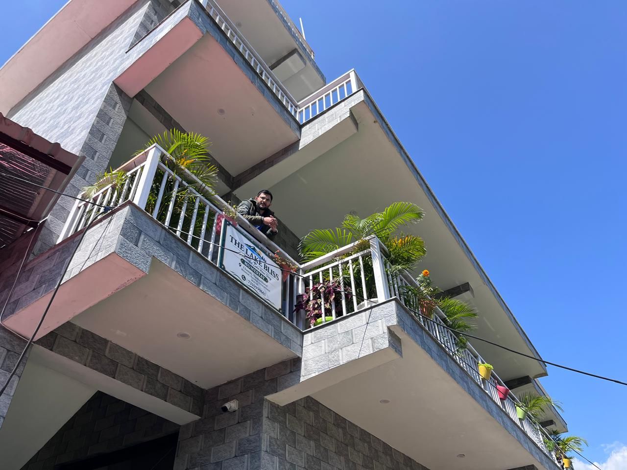 Un edificio de varios pisos con balcones, algunos con barandillas y plantas.