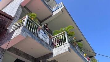 Un edificio de varios pisos con balcones, algunos con barandillas y plantas.
