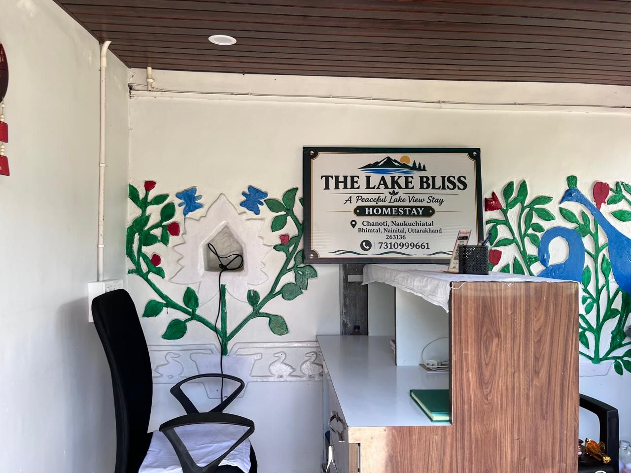 Ein Empfangsbereich mit einem Schild für das Hotel 'The Lake Bliss', inklusive einer Kontaktnummer und Standortangaben.