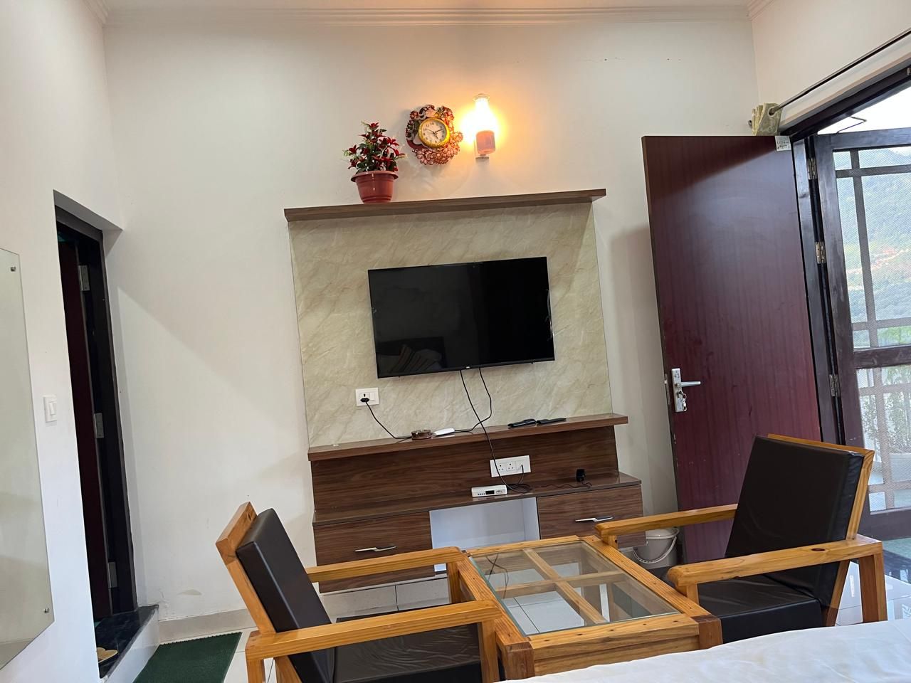 Une pièce dotée d’un téléviseur à écran plat fixé au mur, d’une table en bois avec des chaises, d’une porte et d’une fenêtre.