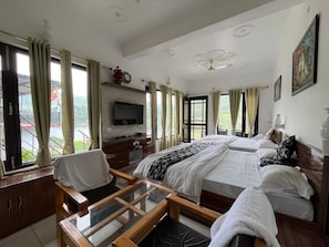 Una camera d'albergo con un letto, comodini, una TV e una finestra con tende.
