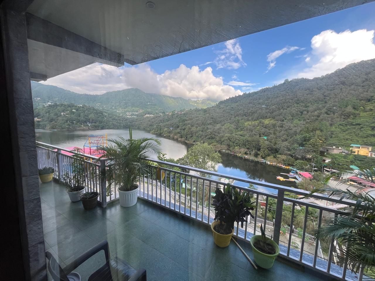 Ein Balkon mit Blumentöpfen, Blick auf einen Fluss und eine gebirgige Landschaft.