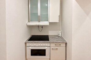 A compact kitchen with a built-in oven, a stovetop, and a microwave. - Your Vienna Reunion 2BR and Lounge for 6 (Vienna)