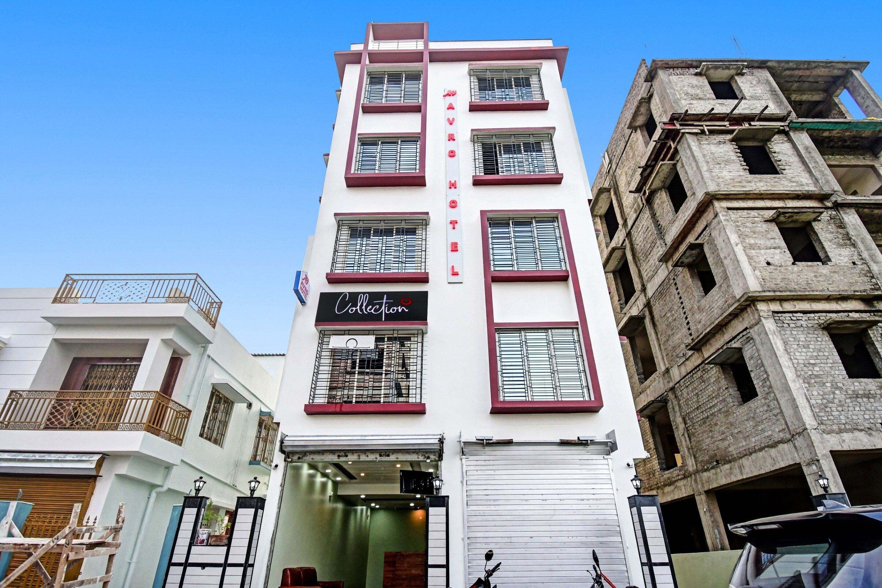 Un hotel con un cartel vertical, varias ventanas con rejas de metal y una entrada de tienda cerrada.