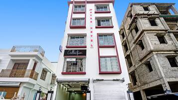 Un hotel con un cartel vertical, varias ventanas con rejas de metal y una entrada de tienda cerrada.