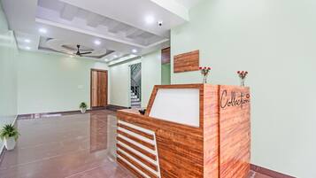 A reception desk with a wooden finish, a ceiling fan, and a staircase in the background.