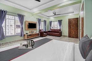 Ein Schlafzimmer mit einem Bett, einem Sofa, einem Fernseher, einem Kleiderschrank und einem Couchtisch mit Tassen.
