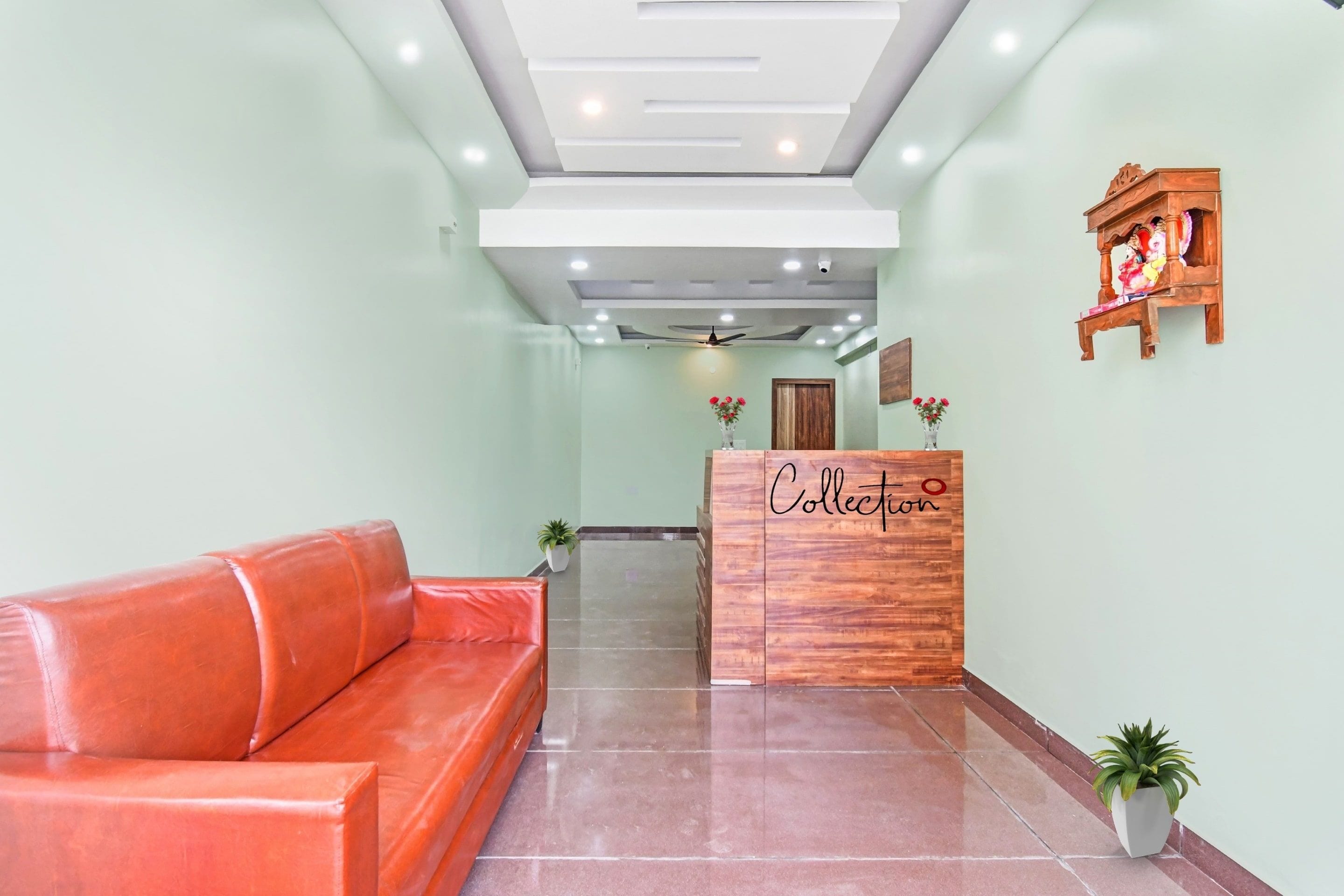 Un área de recepción con un mostrador de madera identificado como 'Collection', un sofá de cuero rojo y un ventilador de techo.