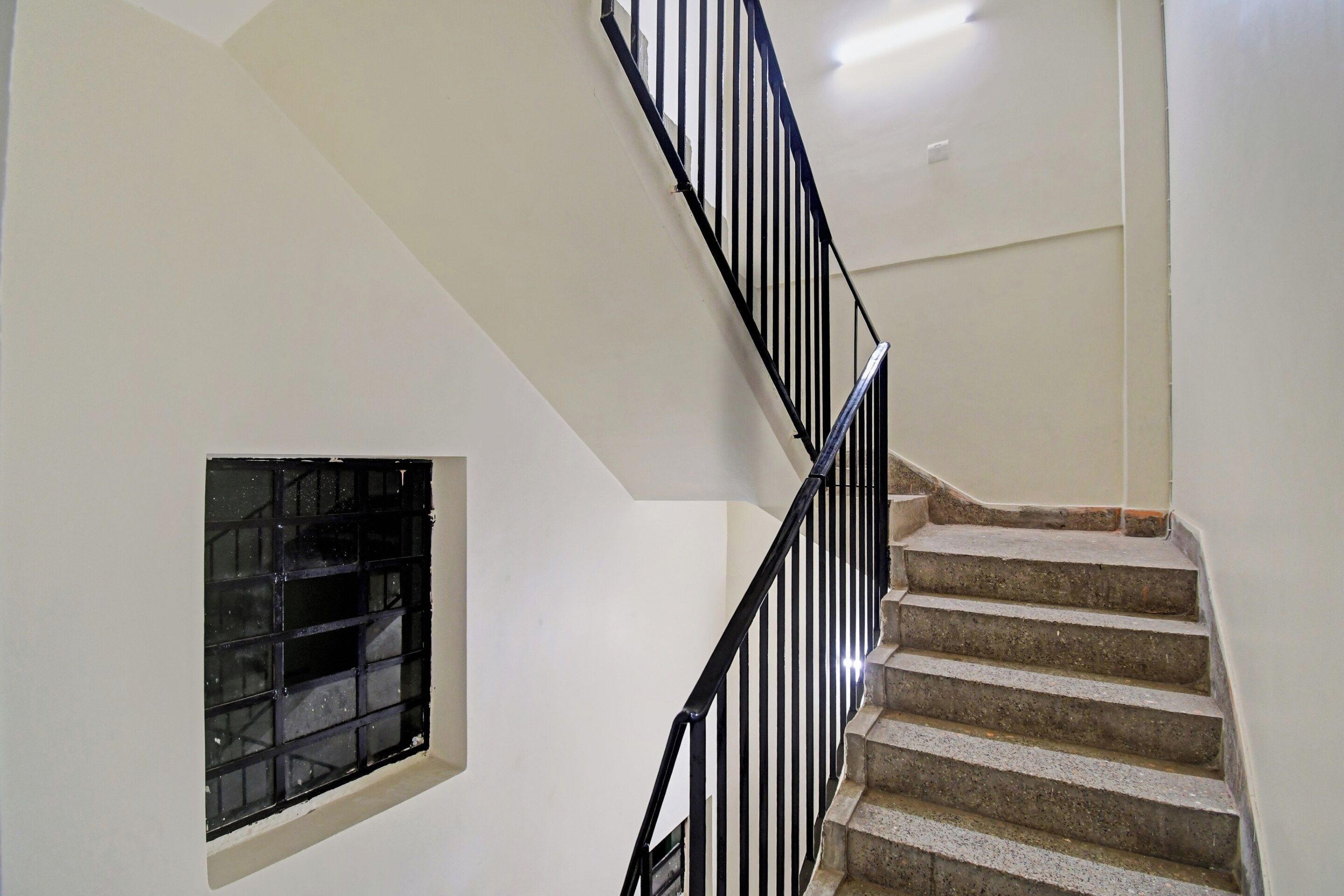A staircase with black railings and beige steps leading to a landing.