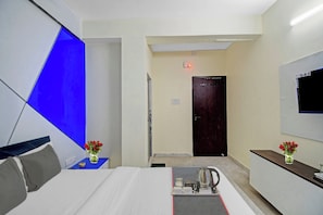 A hotel room with a bed, a desk, a TV, and a door. - Collection O Green Leaf Near Acropolis (Kolkata)