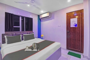 A hotel room with a bed, a nightstand, an air conditioning unit, a wooden door with a sign, and a ceiling fan. - Collection O Green Leaf Near Acropolis (Kolkata)