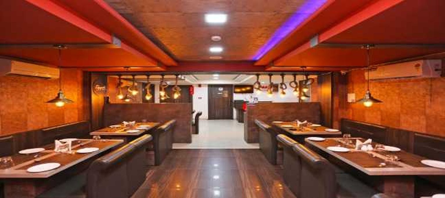A restaurant interior with booths, hanging light fixtures, and a central walkway.