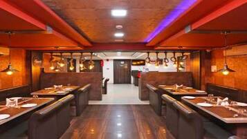 A restaurant interior with booths, hanging light fixtures, and a central walkway.