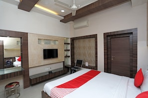 A hotel room with a bed, a desk, a chair, a television, and a wardrobe. - Hotel O South Fern (Kolkata)