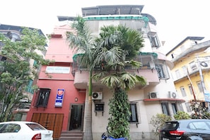 A multi-story building with balconies and a palm tree in front. - Hotel O South Fern (Kolkata)