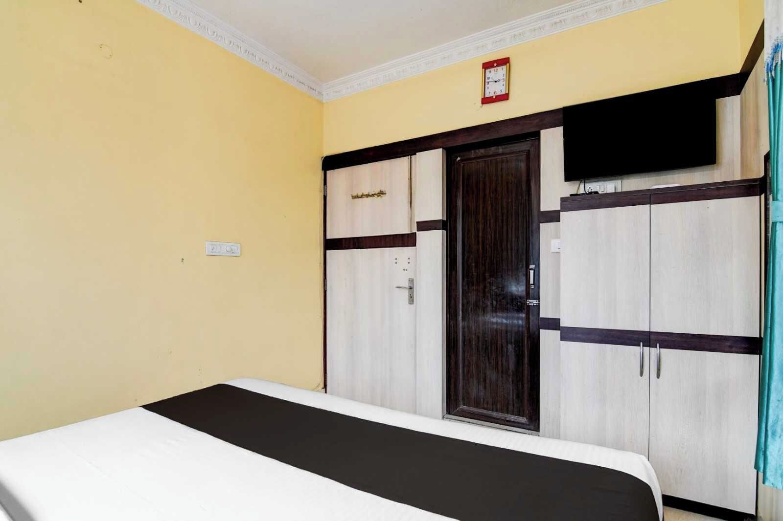 A hotel room with a bed, wardrobe, and a television.
