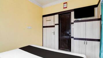 A hotel room with a bed, wardrobe, and a television.