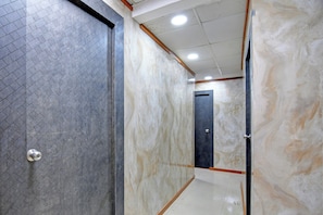 A hallway with a patterned floor, a door with a metallic handle, and a ceiling with recessed lighting. - Hotel O Jalan Regency (Kolkata)