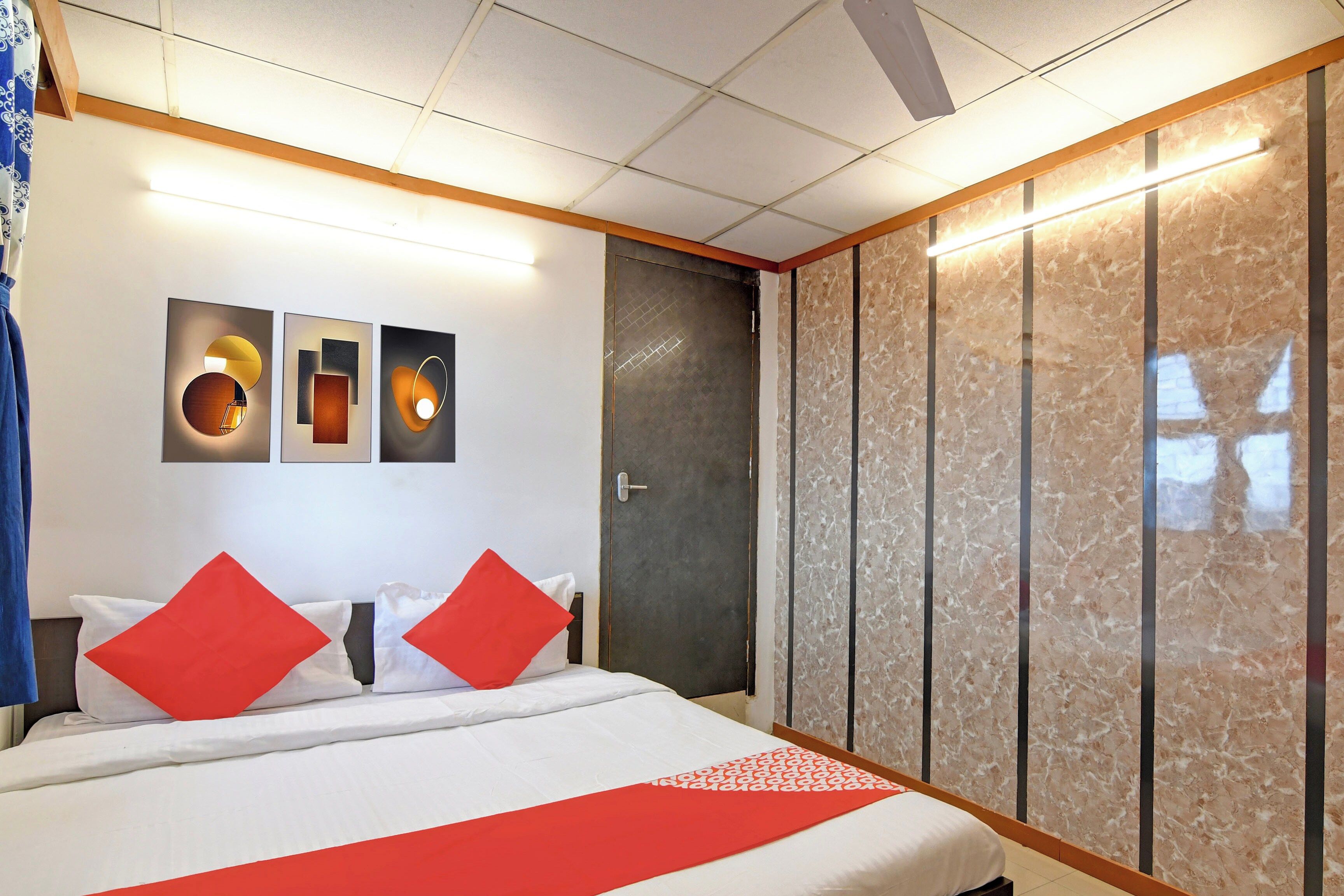 Habitación de hotel con cama, armario y obras de arte en la pared.