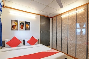 Habitación de hotel con cama, armario y obras de arte en la pared.