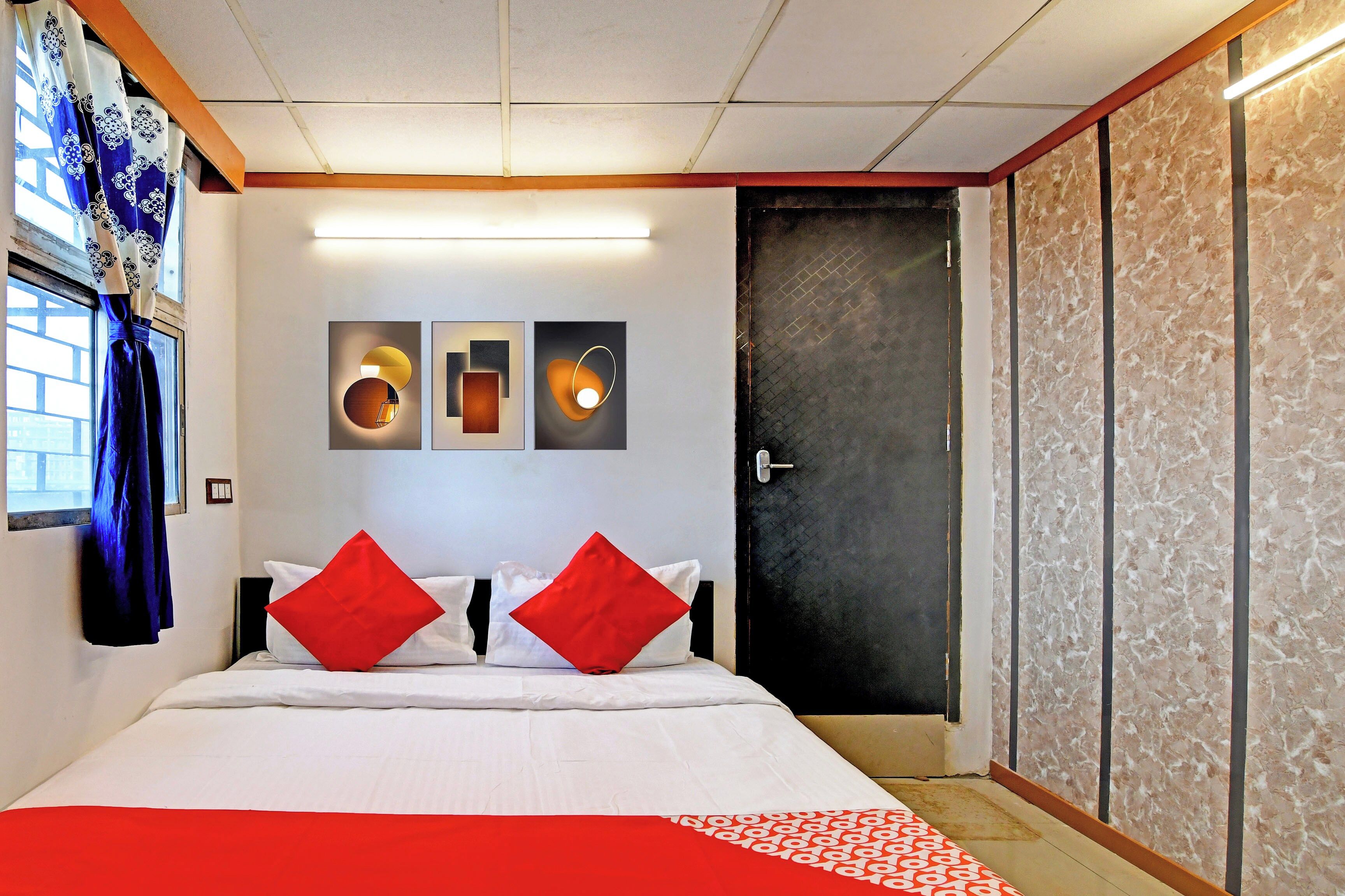 Una habitación de hotel con una cama, una puerta y un muro con tres obras de arte enmarcadas.