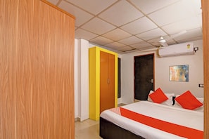Una habitación de hotel con cama, armario, puerta y aire acondicionado.