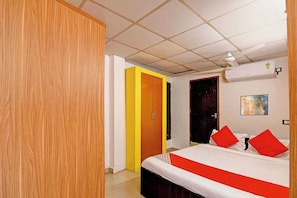 Una habitación de hotel con una cama, un armario, una puerta y un equipo de aire acondicionado.
