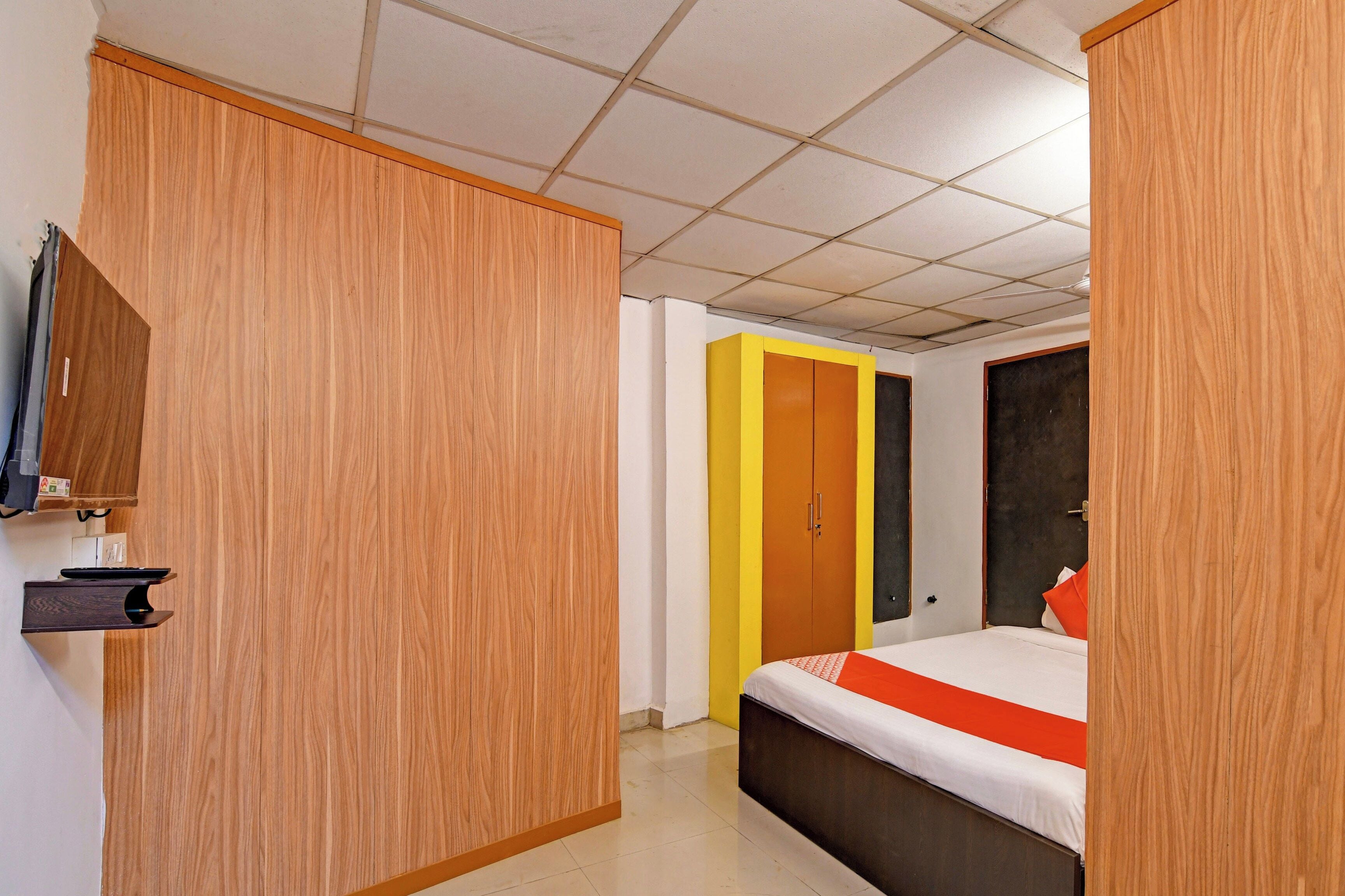 A hotel room with a bed, a desk with a computer, and a wardrobe.