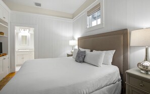 A hotel room with a large bed, a bedside table, a lamp, a wardrobe, and a mirror. - WaterColor | 2 King Suites, Beach & Pools (Santa Rosa Beach)