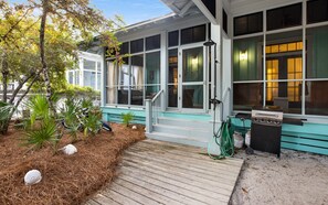 Ein überdachter Außenbereich mit Holzterrasse, Grill und Gartenschlauch.