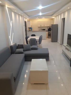 A modern living room with a sectional sofa, a coffee table, and a dining area with chairs and a table. - Avin Resort Hurghada (Hurghada)