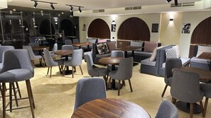 A modern interior with round tables and grey chairs, a sofa, and a bar area. - Avin Resort Hurghada (Hurghada)