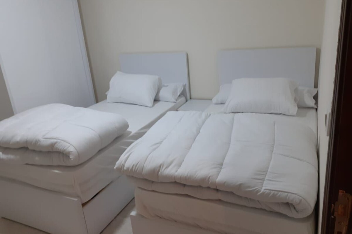 A room with two beds, each with white bedding and headboards.