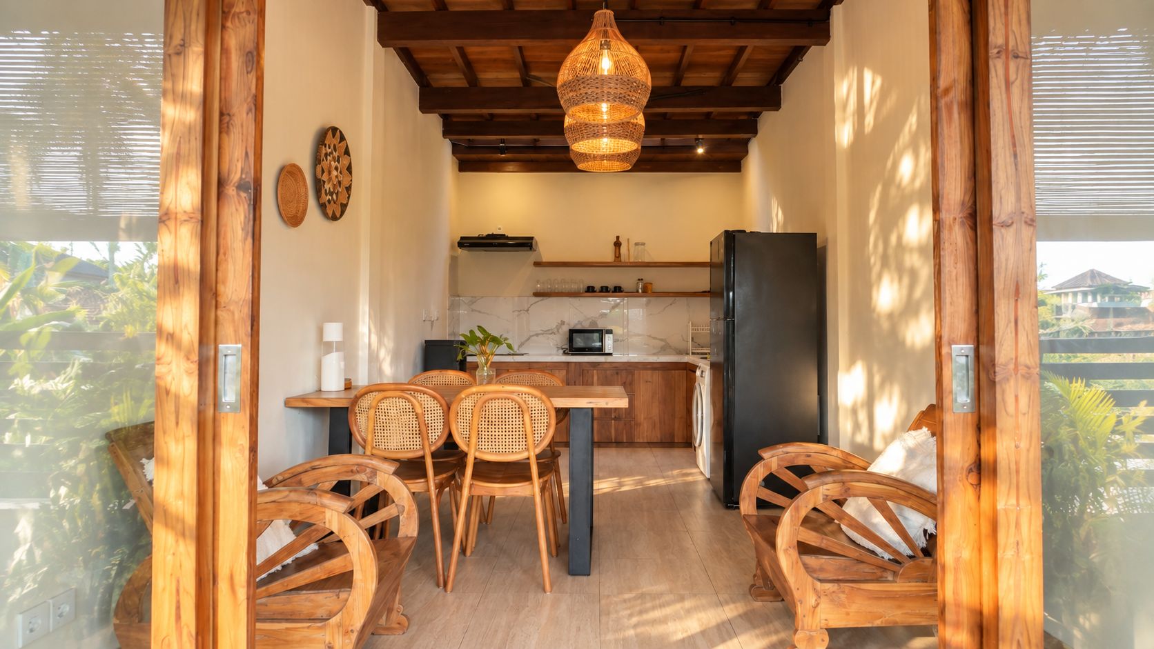 Cozinha com área de refeições, cadeiras de madeira, luminária pendente e geladeira.