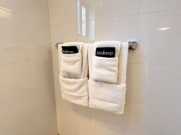 Two white towels with 'Makeup' labels hanging on a metal towel rack in a bathroom with white tiled walls. - Experience this stylish 3BR/2BA Gold Coast condo togheter with your family. Relax on your private covered patio with gas BBQ, or enjoy resort pools, tennis courts and a gym in this gated community. Aruba’s beautiful beaches are just minutes away. (Noord)