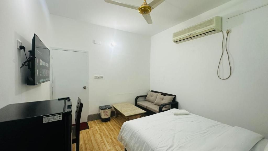 Un dormitorio con cama, escritorio, silla, sofá, ventilador de techo y aire acondicionado.