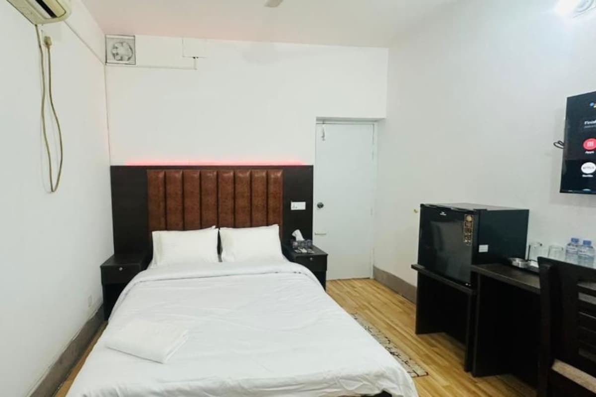 Una camera d'albergo con un letto, una scrivania, un televisore e una porta.