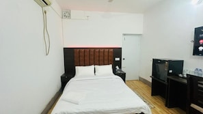 A hotel room with a bed, a desk, a television, and a door. - Chittagong Apartment Service Guest House (Dhaka)