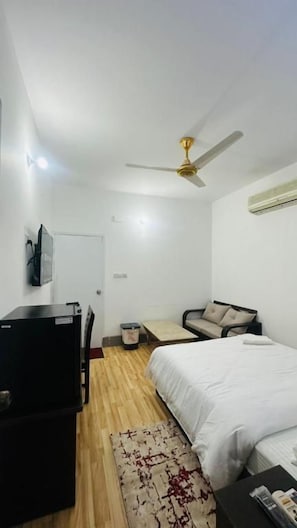Una camera da letto con un letto, una scrivania, una sedia, una ventola a soffitto e un condizionatore d'aria.