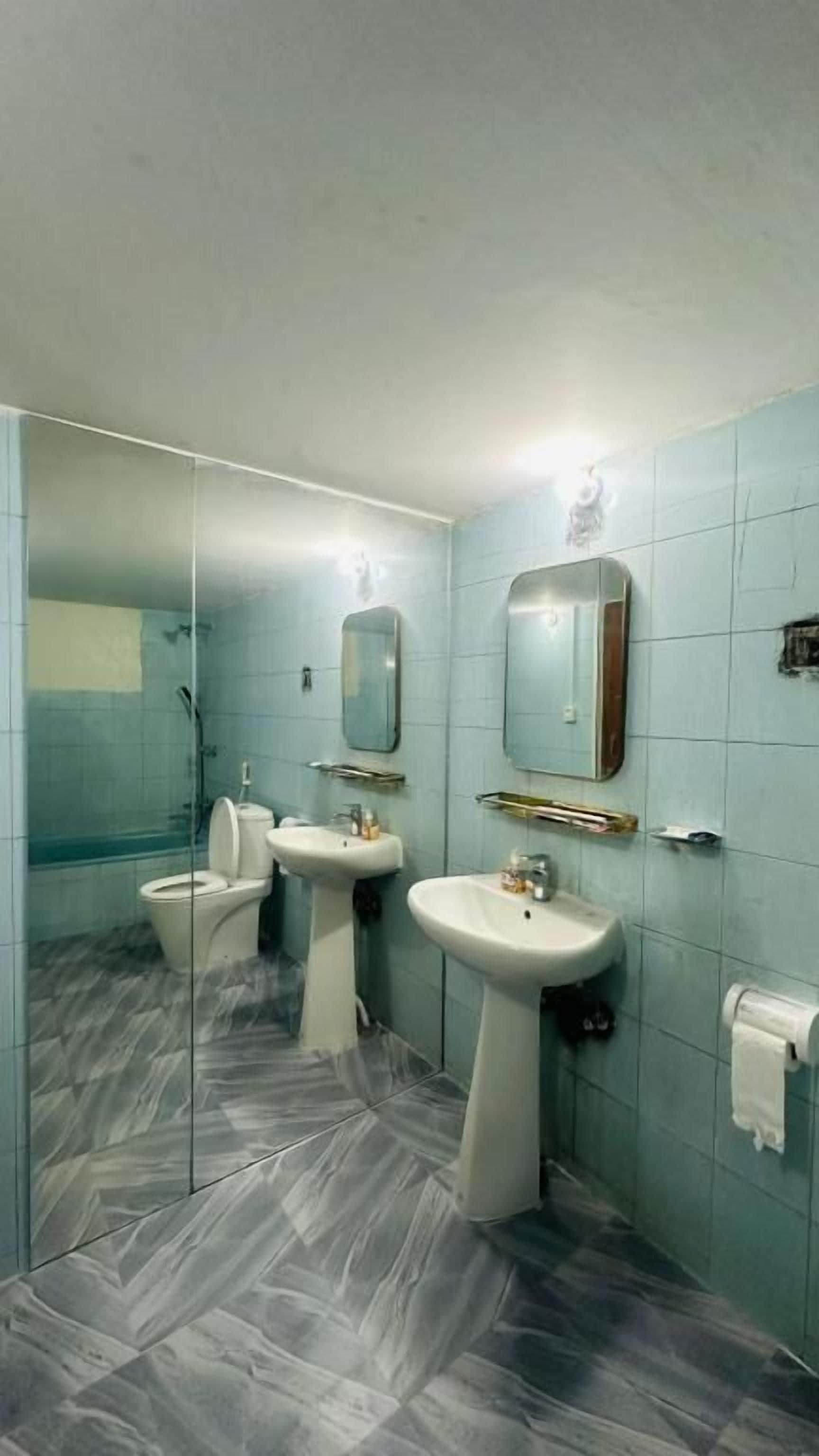 A bathroom with a glass shower enclosure, two sinks, and a toilet.