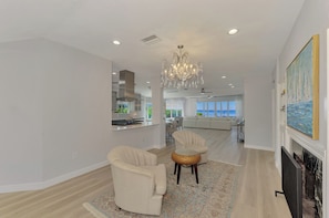 A modern living room with a fireplace, a dining area, and a view of the ocean. - Sarasota Sunset Villa-Luxury waterfront pool home (Sarasota)