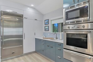 Una cocina moderna con electrodomésticos de acero inoxidable, horno empotrado y ventana con vistas.
